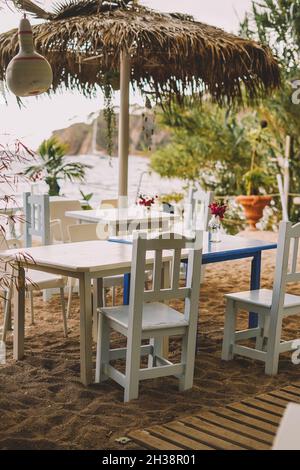 Terrasse avec tables et chaises en bois blanc et palmiers Banque D'Images