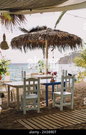 Terrasse avec tables et chaises en bois blanc et palmiers Banque D'Images