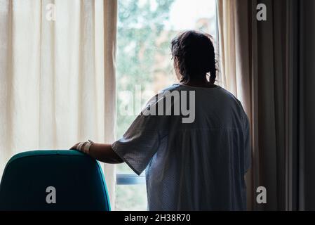 Jeune patient regardant par la fenêtre d'un hôpital. Banque D'Images