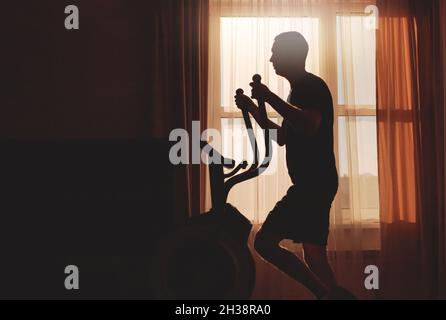 Un homme entre pour le sport à l'aube à la maison, silhouette Banque D'Images