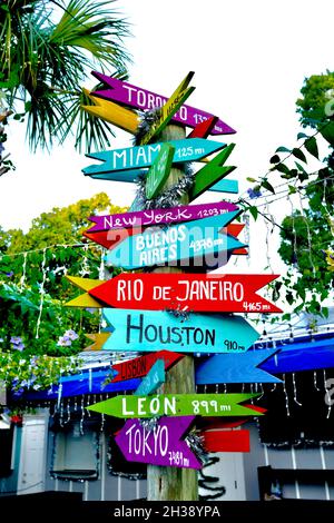 Flèche directionnelle vers divers endroits dans le monde.Fait de flèches en bois sur le montant de l'affiche.Chaque nom de ville a les miles de Key West, FL Banque D'Images