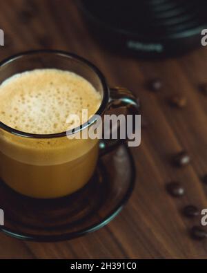 Gros plan d'un café fouetté en verre transparent sur une table en bois Banque D'Images