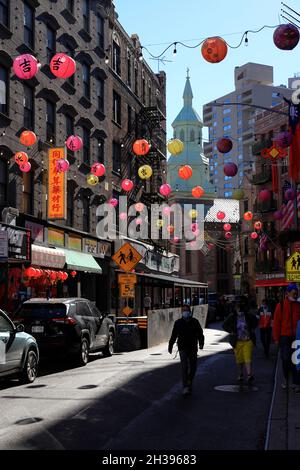Mott Street dans Chinatown avec des lanternes de style traditionnel surplombant la rue et la tour de l'église de Transfiguration en arrière-plan.Manhattan.New York City.USA Banque D'Images