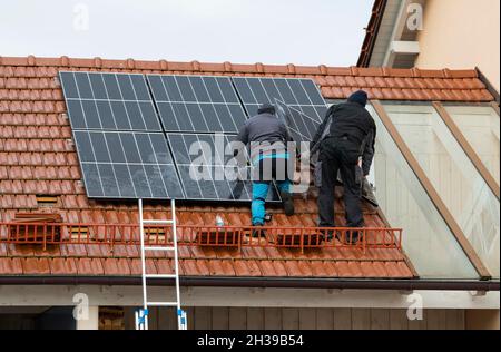 Techniciens assemblant un système photovoltaïque sur le toit d'un immeuble résidentiel à Markt Swabia, Bavière, Allemagne Banque D'Images