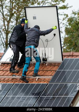 Techniciens assemblant un système photovoltaïque sur le toit d'un immeuble résidentiel à Markt Swabia, Bavière, Allemagne Banque D'Images