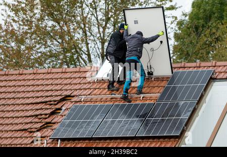 Techniciens assemblant un système photovoltaïque sur le toit d'un immeuble résidentiel à Markt Swabia, Bavière, Allemagne Banque D'Images