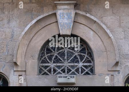 Une fenêtre supérieure semi-circulaire, avec une grille en fer stylisée et un chiffre arabe indiquant l'année de construction dans une porte d'une maison arabe qui a été abandonnée en 1948 dans le quartier de Musrara également connu par son nom hébreu, Morasha dans Jérusalem-Ouest Israël Banque D'Images