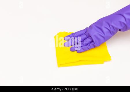 main dans un gant violet avec un chiffon jaune sur fond blanc, gros plan Banque D'Images