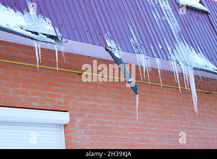 Gouttières brisées.Barrage de glace.Gros plan sur un nouveau système de gouttière cassé sans protection de toit pare-neige sur la construction de la maison.Les glaçons endommagent le toit a Banque D'Images