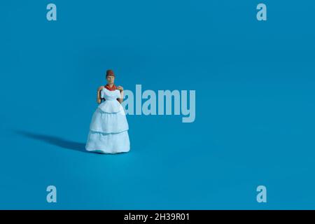 Les femmes miniatures essaient de choisir la robe de mariage sur fond bleu.Photo d'image Banque D'Images