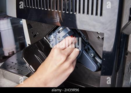 Nettoyage automatique de la machine à café.La femme insère le mécanisme dans la machine à café.Entretien des appareils ménagers Banque D'Images