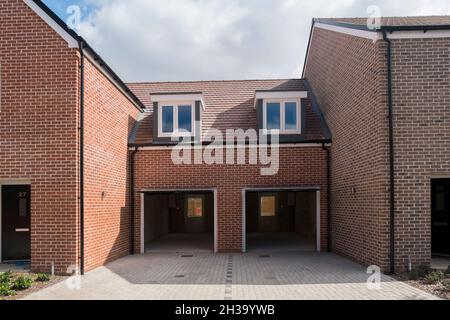 Nouvelles maisons avec garages à Joseph Lancaster Lane, le nouveau développement dans le nord de Chichester, West Sussex, Angleterre, Royaume-Uni. Banque D'Images