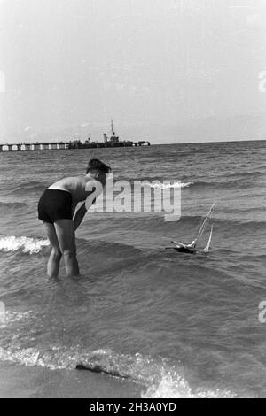 Ein Junge mit seinem Spielzeugboot im Urlaub in der Ostsee, Deutschland 1930 er Jahre. Un garçon avec son jouet bateau à la mer Baltique, Allemagne 1930. Banque D'Images