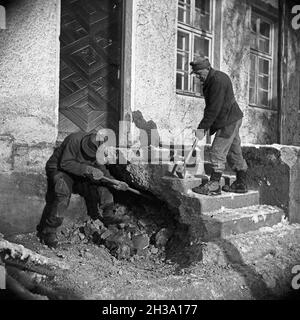 Zwei Männer brechen die Treppe zu einem Hauseingang ab, Deutschland 1950er Jahre.Deux hommes démontant les marches d'une entrée de maison, l'Allemagne des années 1950. Banque D'Images