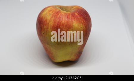 La pomme rouge clair est sur un fond blanc Banque D'Images