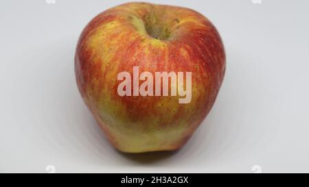La pomme rouge clair est sur un fond blanc Banque D'Images