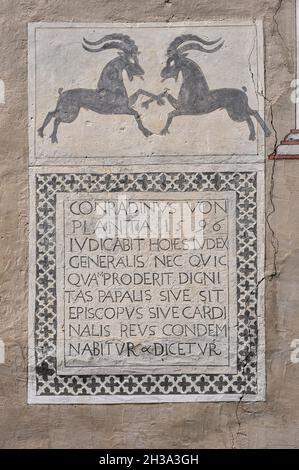 Deux mâles ibexes alpins ou chèvres de montagne paw l'air dans une confrontation au-dessus d'une inscription sgraffito latin datée de 1596 sur la façade d'une maison familiale traditionnelle typique à Ardez, un village historique dans la vallée de l'Engadine basse dans le canton de Grisons ou Grisons, dans l'est de la Suisse.L’ibex alpin ou Capra est le symbole héraldique du canton.L'inscription mentionne un membre de la puissante famille von Planta, les premiers propriétaires enregistrés d'une tour droite du milieu du XIIIe siècle à Ardez. Banque D'Images