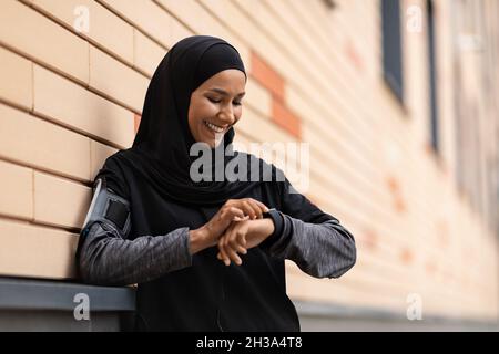 Jeune femme musulmane sportive contrôle de l'activité physique sur Smartwatch après l'entraînement en plein air Banque D'Images