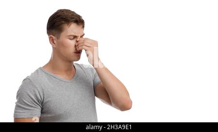 Bouleversé triste homme européen millénaire souffrant d'écoulement nasal ou de maux de tête, touchant le visage Banque D'Images