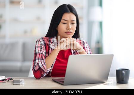 Manque d'inspiration.Femme freelancer asiatique frustrée regardant l'écran d'ordinateur portable Banque D'Images