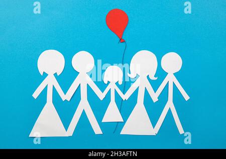 Image conceptuelle du co-parent.Deux familles partagent la garde et le rôle parental ensemble.Deux couples partageant un enfant avec un ballon rouge, feuille de papier. Banque D'Images