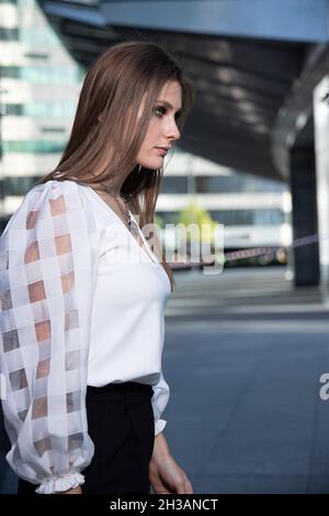 Jeune femme d'affaires dans la rue d'une ville moderne en noir et blanc avec de longs cheveux droits Banque D'Images