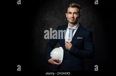 Jeune homme d'affaires caucasien ingénieur architecte, avec un casque de protection blanc en main pour la construction.Gros plan, avec un visage intelligent. Banque D'Images