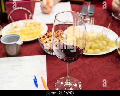 dégustation de vin de raisin rouge - verre de vin avec une portion de vin testé et papier mémo sur table Banque D'Images