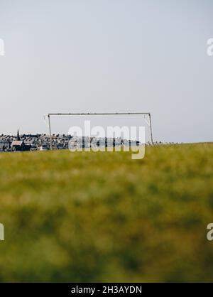 Un seul but de football / football sans filet dans un terrain vide de pelouse d'été avec la ville éloignée de Whitby et des bâtiments derrière. Banque D'Images