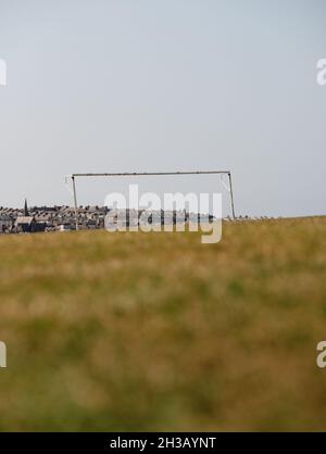 Une vue à angle bas originale d'un seul but de football / football sans filet dans un terrain d'été vide avec une ville hors foyer et un arrière-plan de bâtiments Banque D'Images