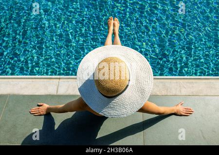 femme avec chapeau de paille pour bronzer et se détendre au bord de la piscine. vue de dessus Banque D'Images