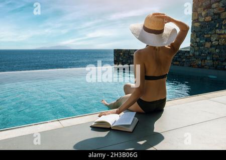 femme de bains de soleil et de détente au bord de la piscine avec vue sur la mer dans villa de luxe Banque D'Images