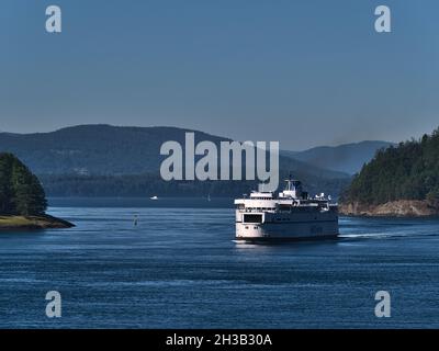 Vue du navire RORO MV Queen of New Westminster de BC Ferries approchant entre les îles de la mer de Salish le jour ensoleillé de l'automne. Banque D'Images