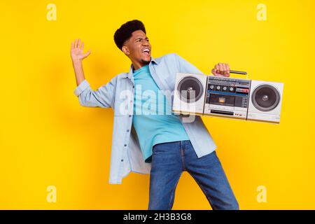 Photo de funky cool Dark peau homme porter Jean chemise écoute boombox chant danse isolé couleur jaune fond Banque D'Images