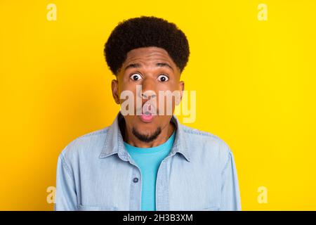 Photo de funky choqué peau sombre gars habillé denim chemise grands yeux isolé couleur jaune fond Banque D'Images