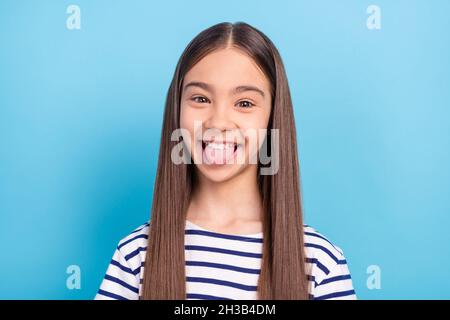 Photo portrait petite fille portant une chemise rayée souriant dupe montrant la langue isolé pastel couleur bleu fond Banque D'Images