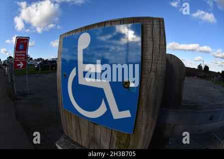 Vue en angle d'un panneau bleu pour personnes handicapées reflétant le ciel bleu montrant l'entrée de stationnement pour personnes handicapées Banque D'Images