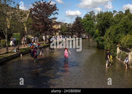 Les familles jouent dans la rivière Windrush qui traverse le magnifique village de Bourton on the Water, Cotswolds, United Kigdom. Banque D'Images