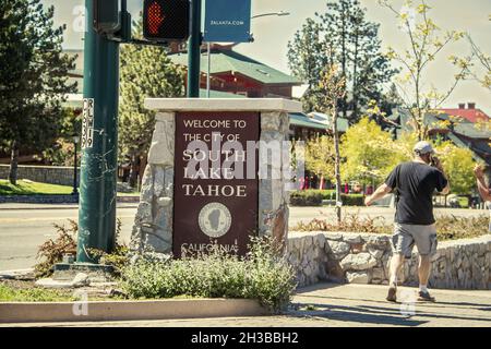 06 01 2021 South Lake Tahoe USA - panneau Bienvenue à South Lake Tahloe California sur un coin de rue avec homme en short sur téléphone à pied - mouvement blu Banque D'Images