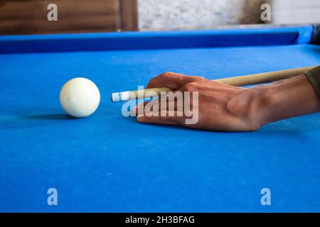 Homme jouant au billard, gros plan de l'homme main se préparant à frapper des boules de billard en utilisant le CUE. Banque D'Images