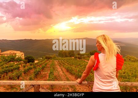 Arrière de la femme regardant les rangées de raisins en terrasse au coucher du soleil de la ville toscane de Montalcino en Italie.Champs toscans dans les vignobles italiens et Banque D'Images