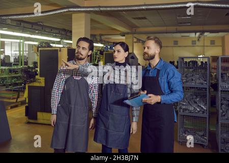 Groupe de travailleurs qui donne au propriétaire ou à l'inspecteur une visite de l'usine de fabrication de chaussures Banque D'Images