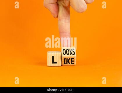 Ressemble à un symbole.Homme d'affaires transforme un cube en bois avec les mots « ressemble à ».Magnifique arrière-plan orange.Affaires, citations populaires et ressemble à conce Banque D'Images