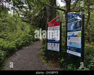 Panneau d'information avec avertissement au point de départ du sentier Wild Pacific Trail à Ucluelet, sur l'île de Vancouver, entouré de forêt tropicale.Concentrez-vous sur le panneau de gauche. Banque D'Images