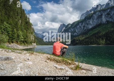 Homme appréciant les montagnes de Dachstein se reflète dans le lac de Gosau, en Autriche Banque D'Images