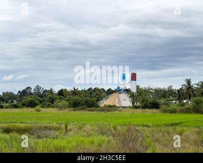 L'usine de groupage de béton avec la petite grue travaille dans le chantier de construction près du champ de paddy dans la zone de campagne, vue de face avec le Banque D'Images