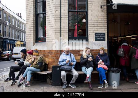 Londres, Royaume-Uni - 20 novembre 2020, les gens s'assoient sur un banc près d'un café qui boit du café Banque D'Images