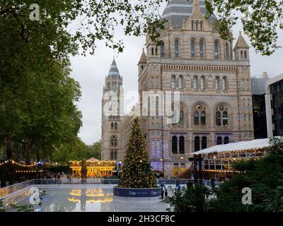 Londres, Grand Londres, Angleterre, octobre 26 2021 : patinoire de fête au Musée national d'histoire avec arbre de Noël et Joyeux tour. Banque D'Images