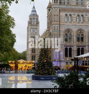 Londres, Grand Londres, Angleterre, octobre 26 2021 : patinoire de fête au Musée national d'histoire avec arbre de Noël et Joyeux tour. Banque D'Images