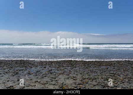 Vue floue sur les galets mouillés sur une plage avec l'océan pacifique Banque D'Images